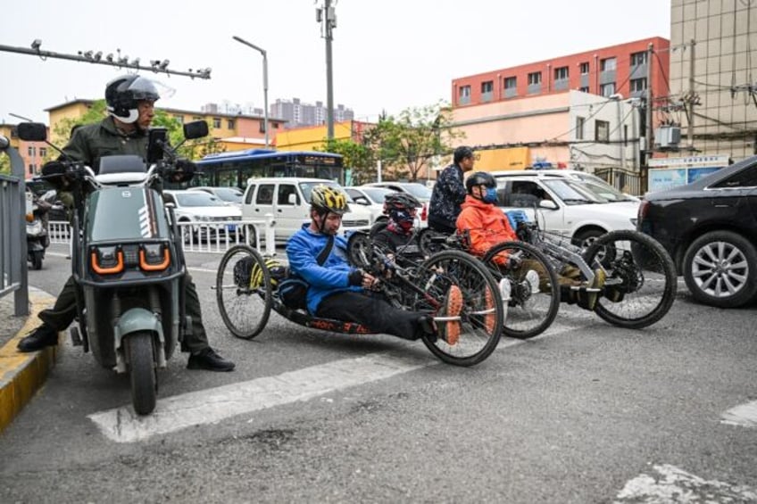 Pan Yifei (R), Wang Feng(C) and Joshua Dominick (L) ride handcycles on a street in Hohhot,