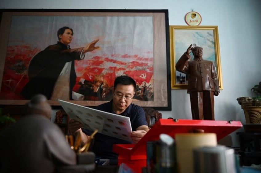 Former soldier and Mao memorabilia collector Feng Gang looks at his displays of pins featu