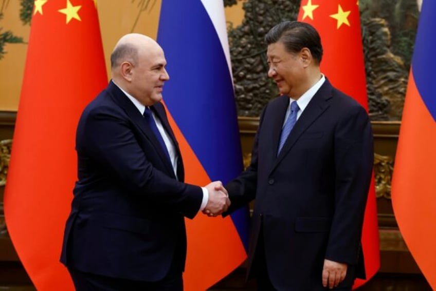 Russian Prime Minister Mikhail Mishustin (L) and Chinese President Xi Jinping shake hands before their meeting Wednesday in Beijing