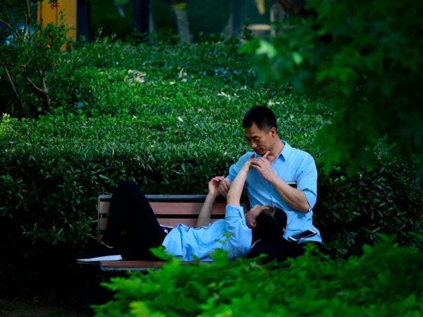 A couple chats on a bench in Beijing on May 29, 2018. (Photo by WANG ZHAO / AFP) (Photo credit should read WANG ZHAO/AFP/Getty Images)