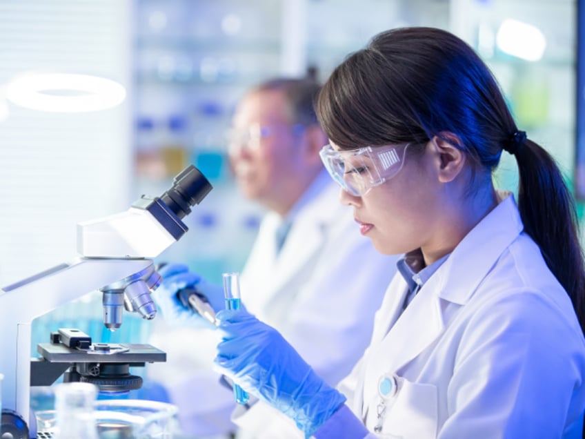 Asian woman scientist conducts an experiment in a laboratory (Stock photo via Getty).