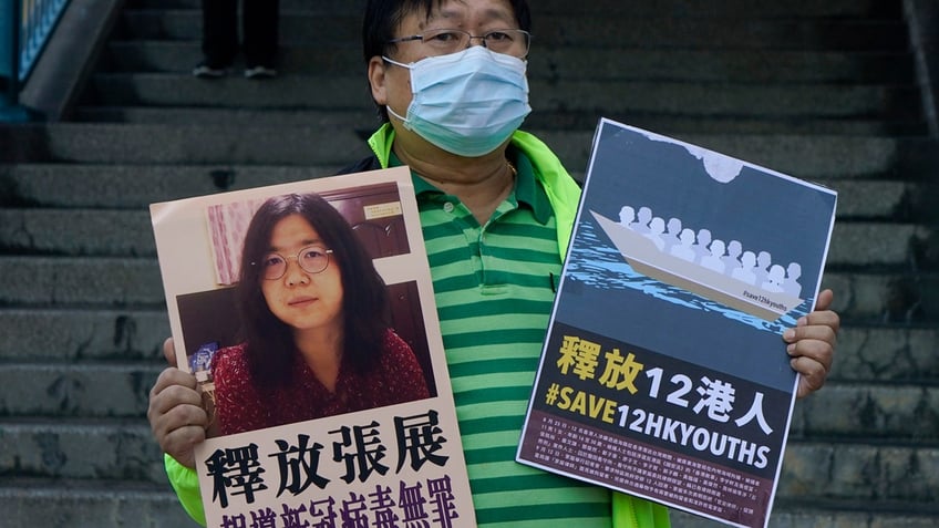 A pro-democracy activist holds placards with a picture of Chinese citizen journalist Zhang Zhan outside the Chinese central government's liaison office in Hong Kong