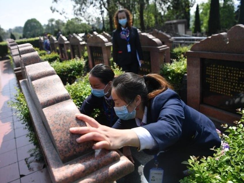 Staff sweep tombs on behalf of deceased's relatives during a remote tomb-sweeping ritual at Mopanshan cemetery on March 31, 2020 in Chengdu, Sichuan Province of China. The cemetery in Chengdu offers remote tomb-sweeping services ahead of Qingming Festival, for people who can't sweep tombs in person amid novel coronavirus outbreak. …