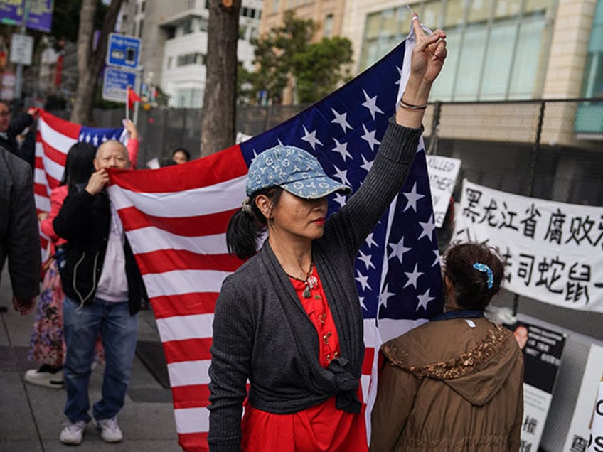 A woman walks with a US flag ahead of the arrival of China's President Xi Jinping ahead of