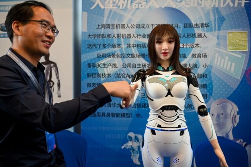 An exhibitor shakes hands with a humanoid robot at the 2024 China Humanoid Robot Developer