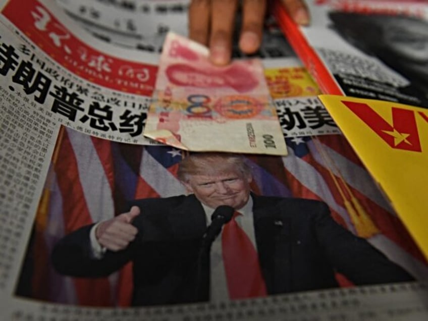 A vendor picks up a 100 yuan note above a newspaper featuring a photo of US president-elec