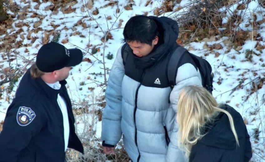 This handout photo released by the Riverdale Police Department on January 1, 2024 shows authorities speaking to Kai Zhuang near the site where he was found in the mountains near Brigham City, Utah, on December 31, 2023, after being reported missing