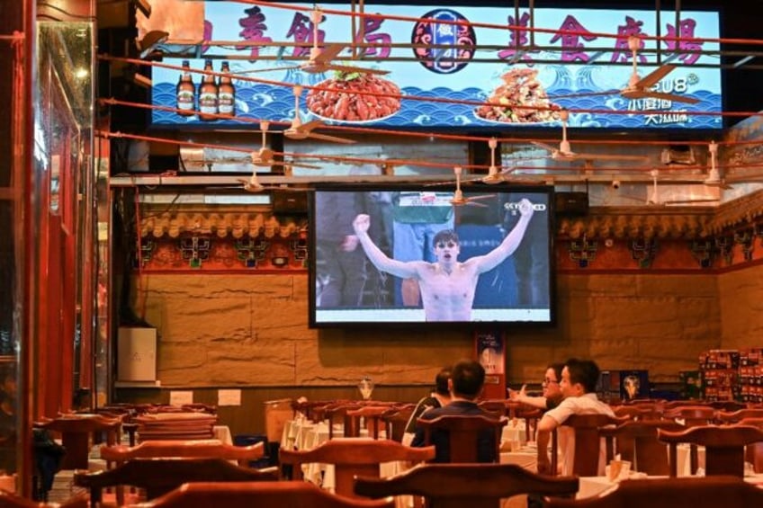 Diehard sports fans at a Beijing restaurant watch Pan Zhanle take gold in a 100m freestyl