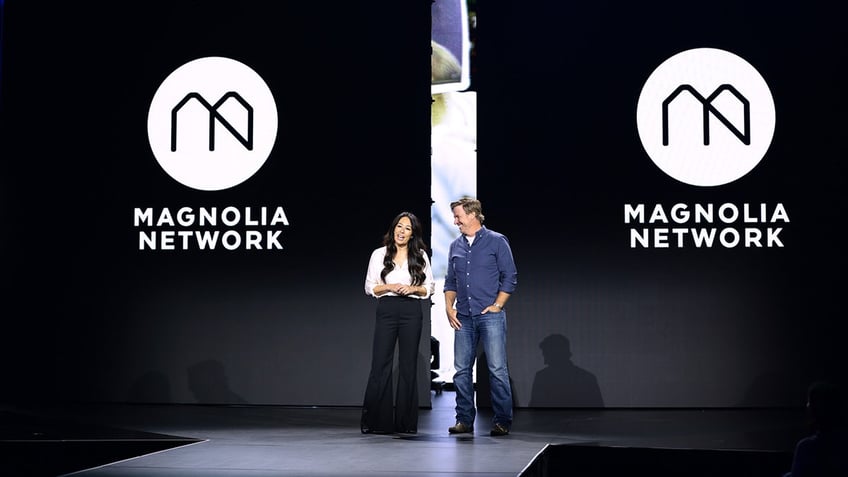 Chip and Joanna Gaines standing in front of Magnolia Network signage