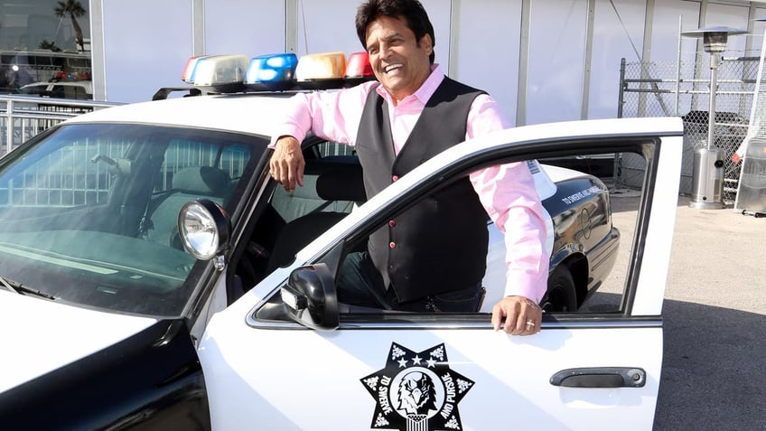 erik estrada posing with police car 