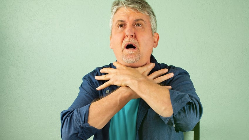 A man choking shows universal choking sign