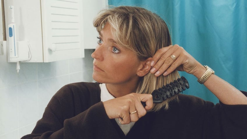 A woman brushes her hair with a vented hairbrush