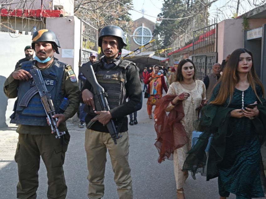 Security personnel stand guard as Christian devotees leave after attending a Christmas mas