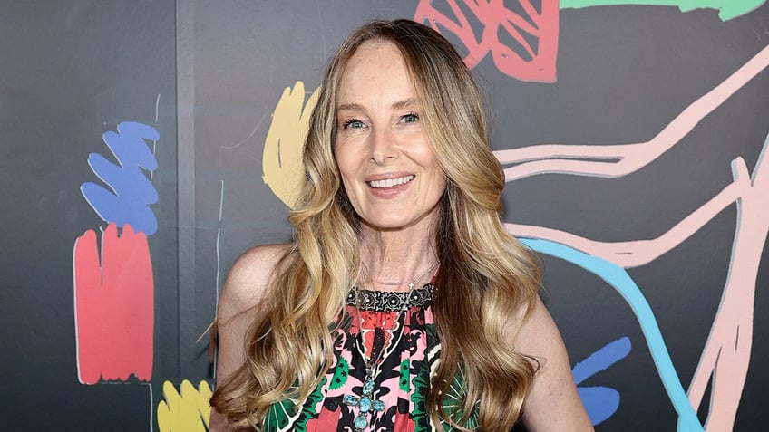Singer Chynna Phillips smiles wearing a colorful dress.