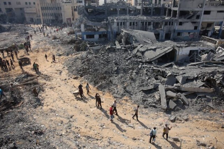 Palestinian civilians walk past the ruins of bombed out buildings in Gaza City's Al-Sinaa