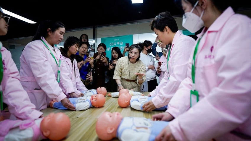 Women train with plastic baby dolls as they take part in a nursing skills class