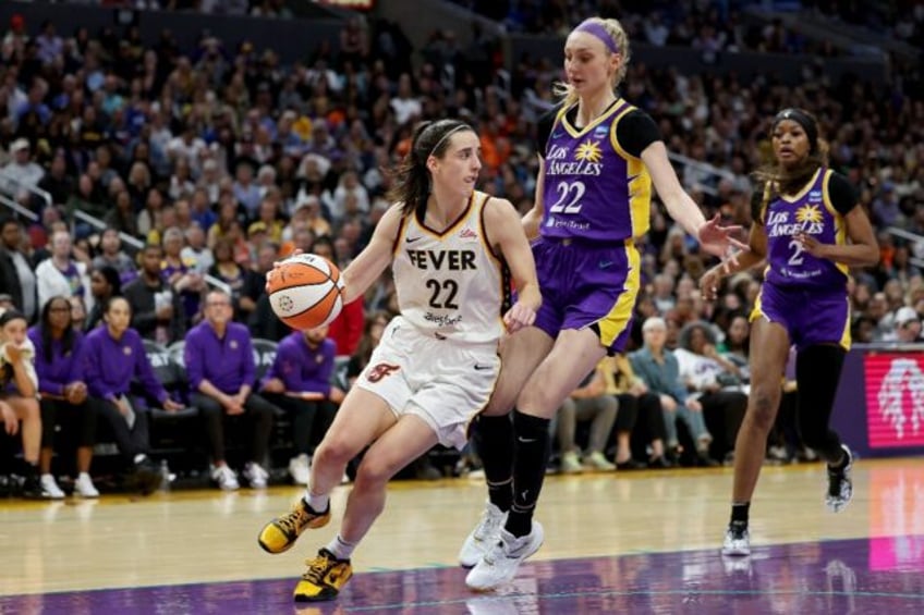 Caitlin Clark of the Indiana Fever drives to the basket against Cameron Brink in the Fever