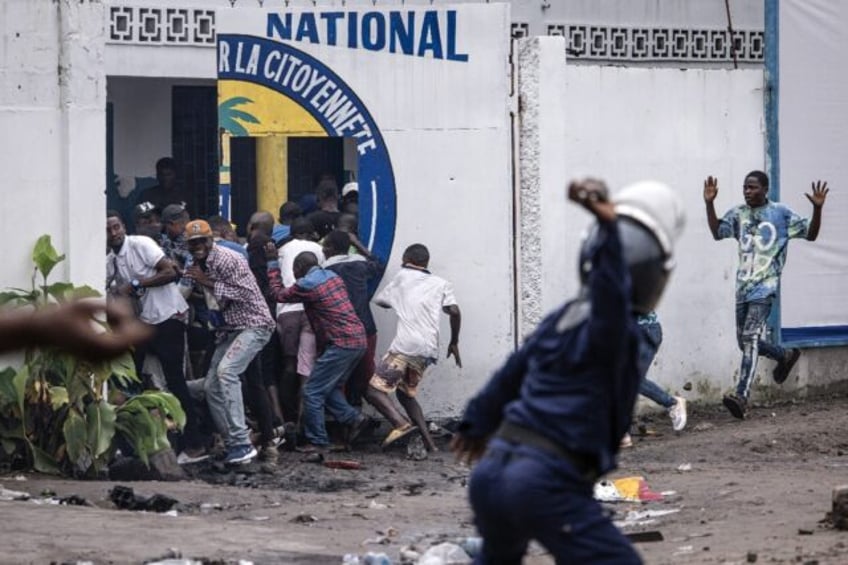 A police officer throws a rock at opposition supporters outside their party HQ in Kinshasa