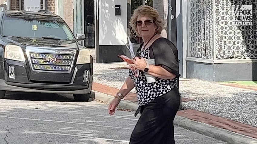 Becky Hill carries papers, her phone and a drink as she heads towards a white truck