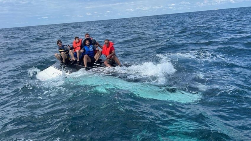 men atop capsized boat