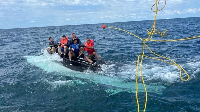 men atop capsized boat