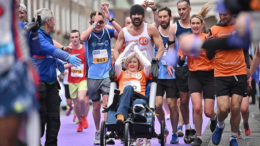 Colin Farrell pushes Emma Fogarty in a wheelchair across finish line at Dublin marathon.