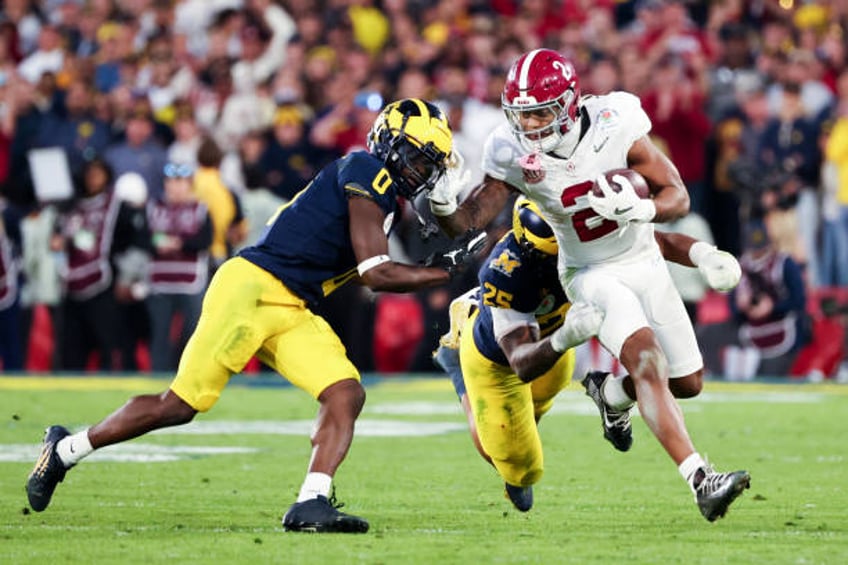 Alabama Crimson Tide running back Jase McClellan runs the ball while defended by Michigan Wolverines linebacker Junior Colson and defensive back Will...