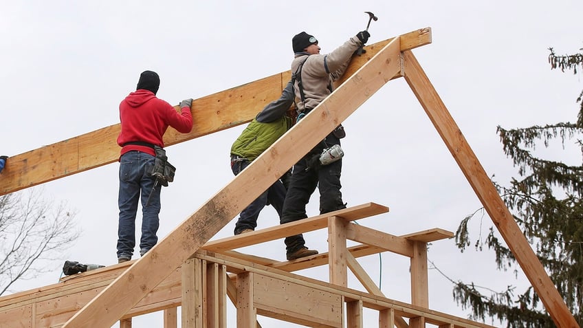 workers frame roof of house