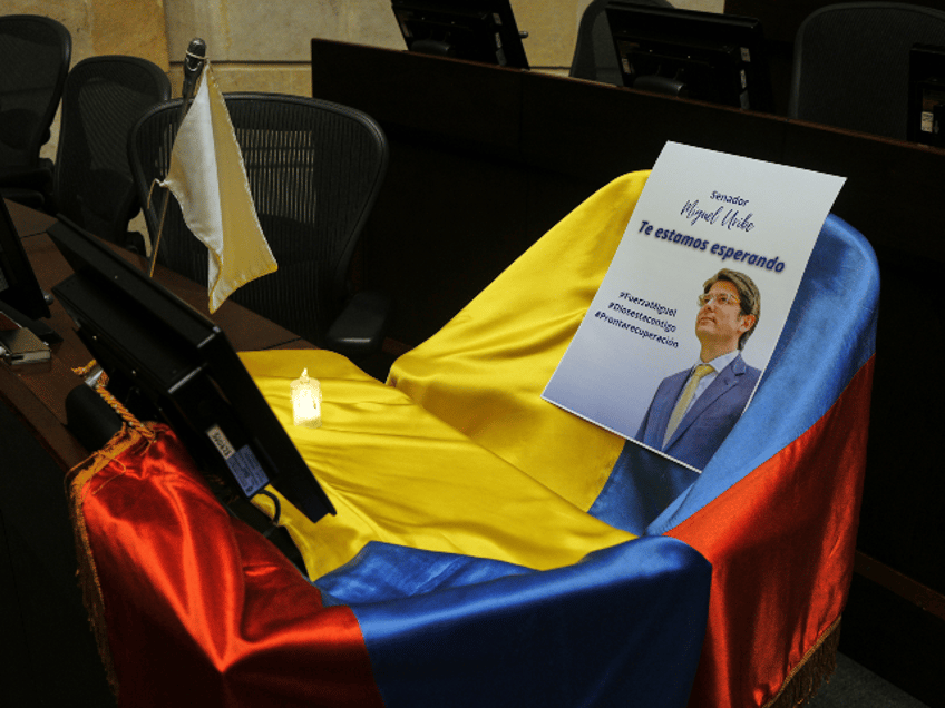 A picture of Colombian Senator Miguel Uribe Turbay and Colombian flag cover his seat at Congress while he is in critical condition after being shot at a political rally in Bogota, Colombia, Monday, June 9, 2025. (AP Photo/Ivan Valencia)
