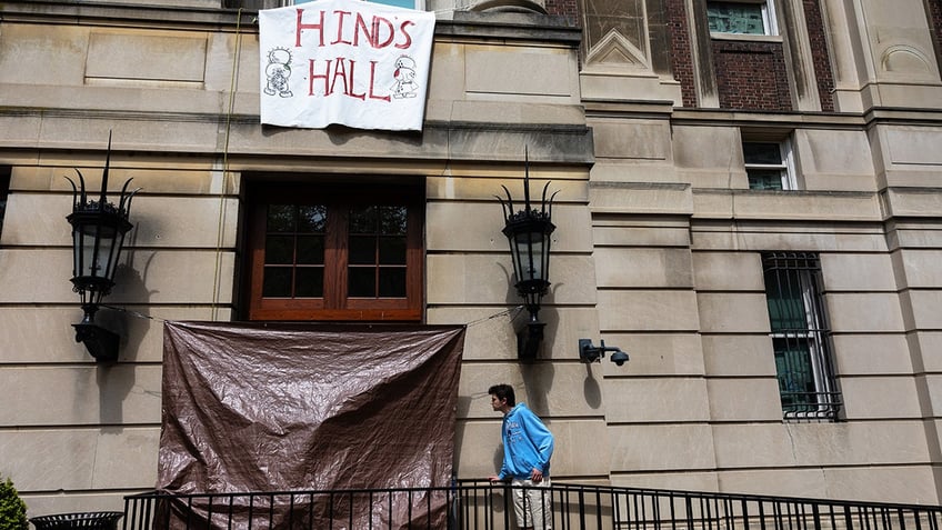 A Columbia student looks at damage to windows of a door at Hamilton Hall at Columbia University