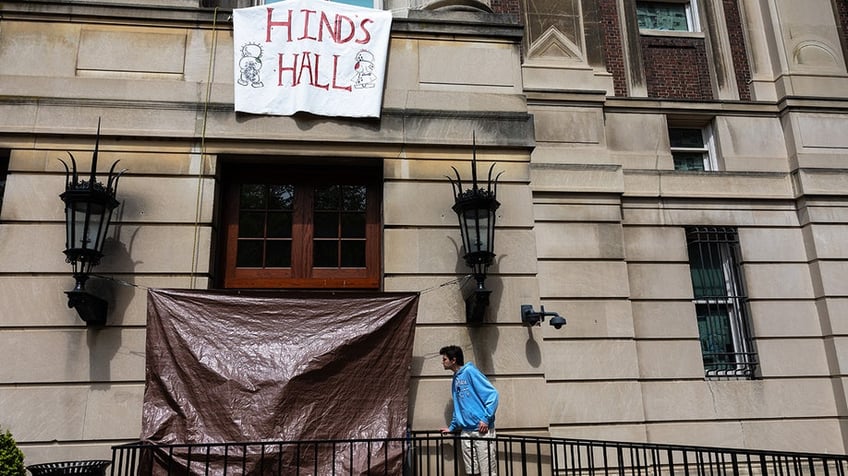 A Columbia student looks at damage to windows of a door at Hamilton Hall at Columbia University