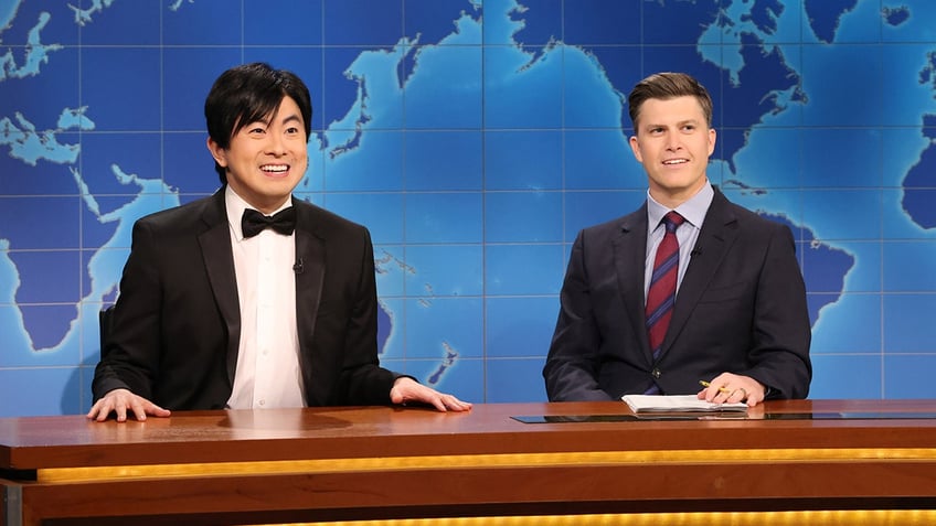 Bowen yang wears a suit while joking with Colin Jost