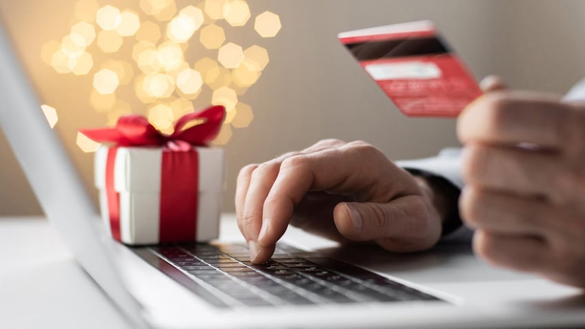 man holding credit card and on laptop