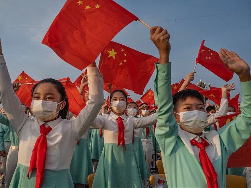 BEIJING, CHINA - JULY 01: Chinese students wave party and national flags at a ceremony mar