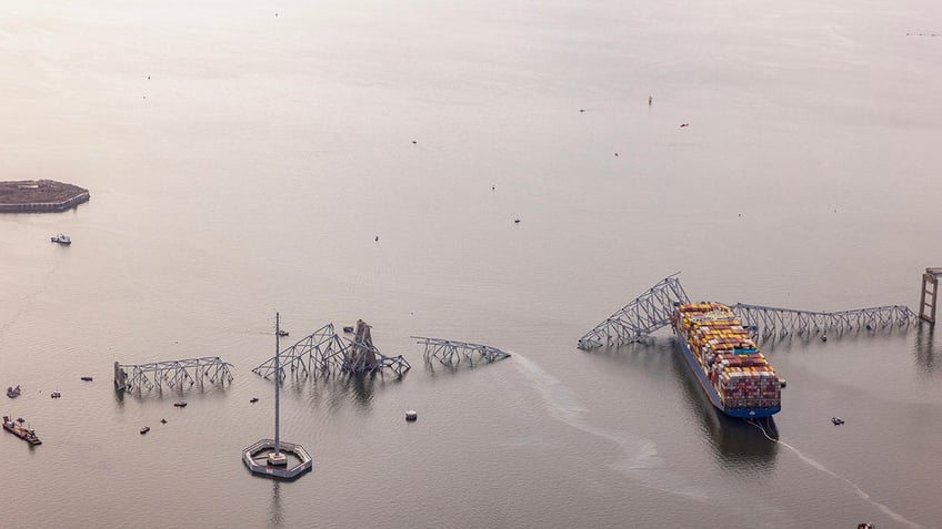 In an aerial view, the cargo ship Dali sits in the water after running into and collapsing the Francis Scott Key Bridge