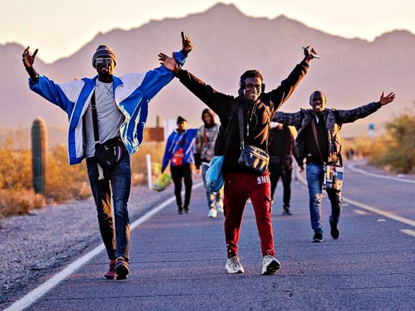 LUKEVILLE, ARIZONA - DECEMBER 07: Immigrants from the west African nation of Guinea strike a celebratory pose after successfully crossing the U.S.-Mexico border on December 07, 2023 in Lukeville, Arizona. A surge of immigrants illegally passing through openings cut by smugglers in the border wall has overwhelmed U.S. immigration authorities, …