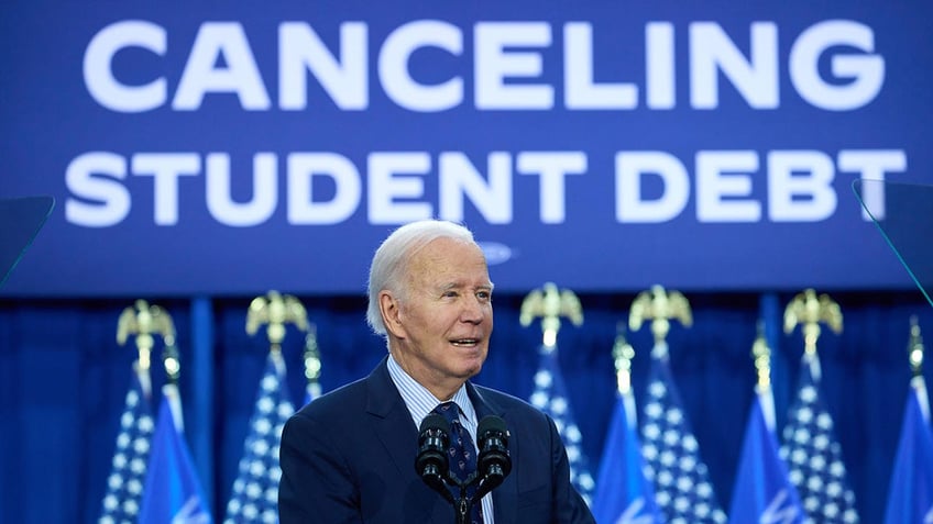 Biden stands in front of banner on canceling student debt