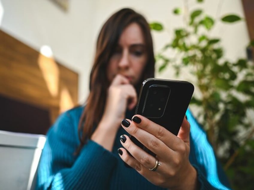 A woman considers a text message that might be a scam