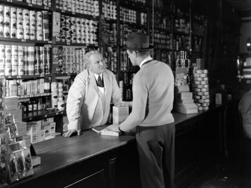 1930s 1940s TWO MEN CUSTOMER AND CLERK IN GENERAL STORE TALKING OVER COUNTER (Photo by H.