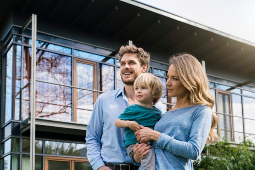 Germany, portrait of smiling family of father, mother and cute toddler boy standing in gar