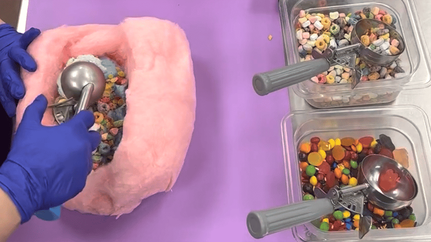 Woman scooping ice cream into a hollowed out piece of cotton candy.