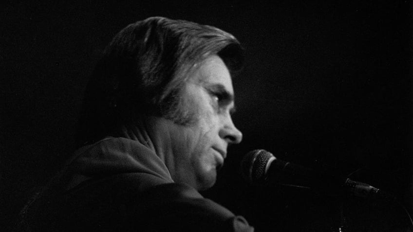 A side profile of George Jones facing a mic