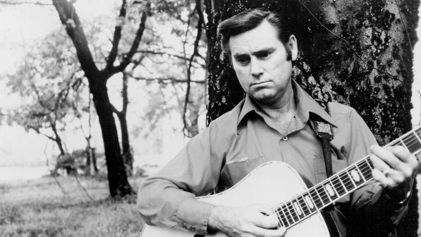 George Jones holding a guitar and playing.