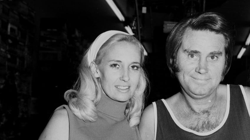 George Jones and Tammy Wynette posing next to each other and smiling