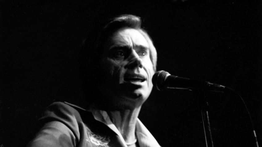 A close-up of George Jones singing to a mic.