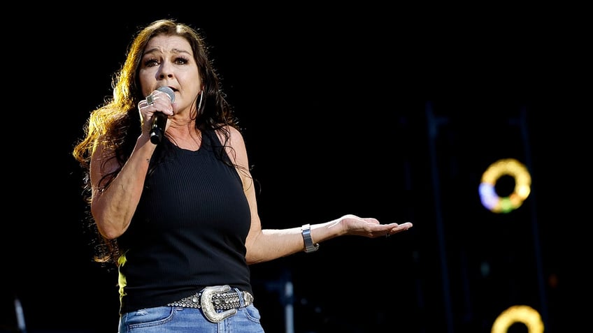 Gretchen Wilson in a black tank top and jeans sings on stage