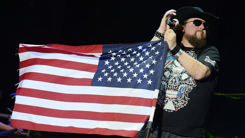 Country star Colt Ford holds a microphone with an American Flag draped around