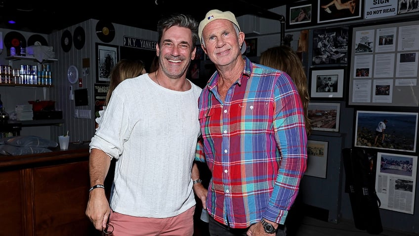 Actor Jon Hamm smiles next to Chad Smith in the Hamptons