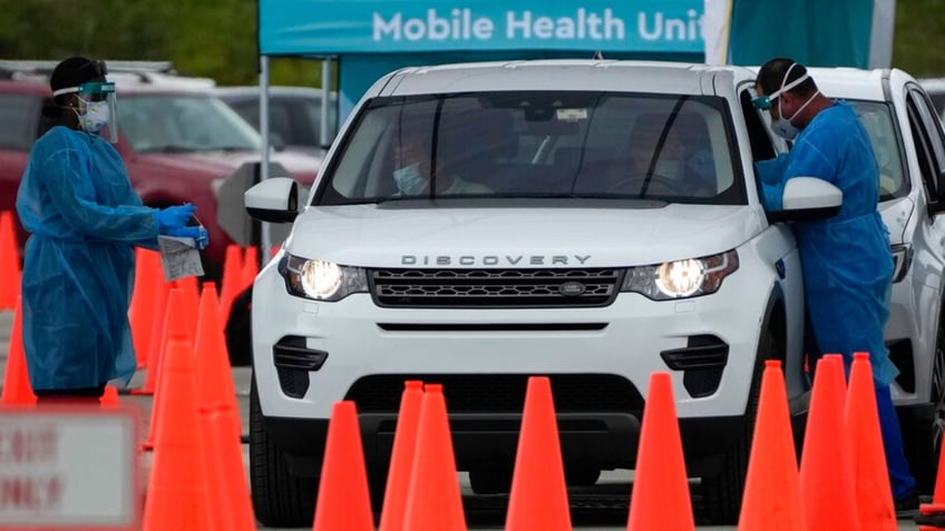 Healthcare workers administer nasal swabs to drivers and passengers at a drive-through COVID-19 testing site at Zoo Miami, Monday, Jan. 3, 2022, in Miami. (AP Photo/Rebecca Blackwell) 