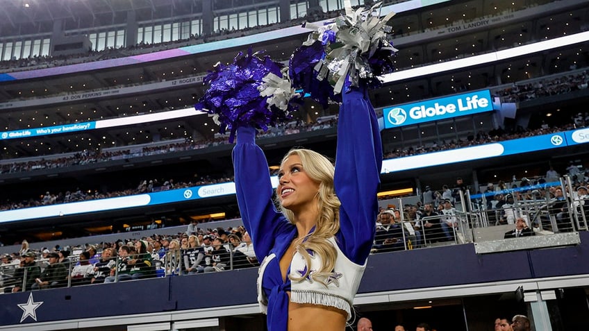 Cowboys cheerleader with pom-poms in air